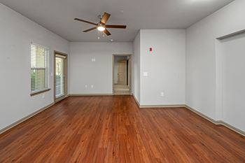 A room with a ceiling fan and wooden floors.
